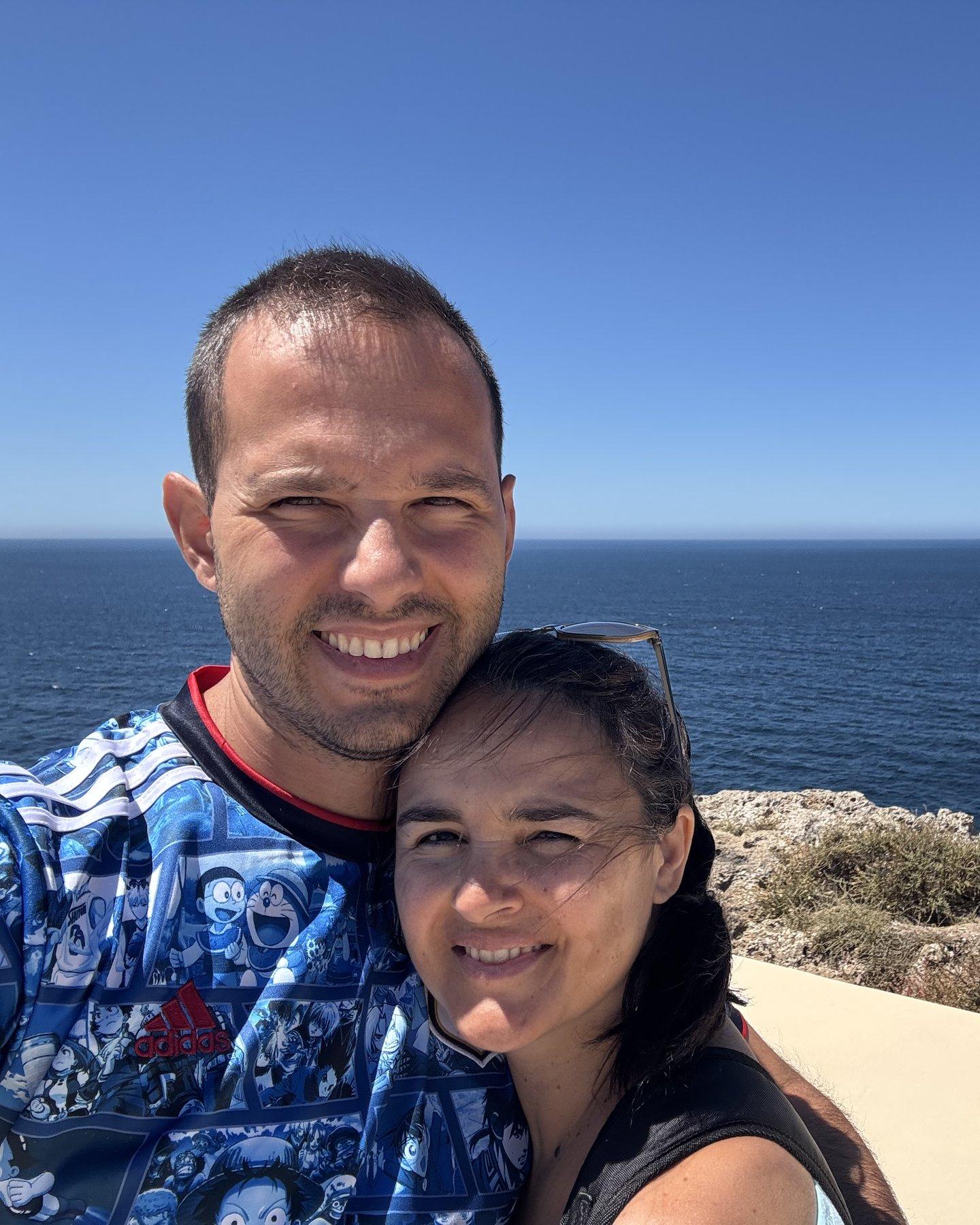 João e Susana, sorridentes, com o mar e a costa rochosa ao fundo